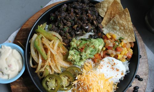 burrito bowl with beans, cheese, onions, rice and tortilla chips