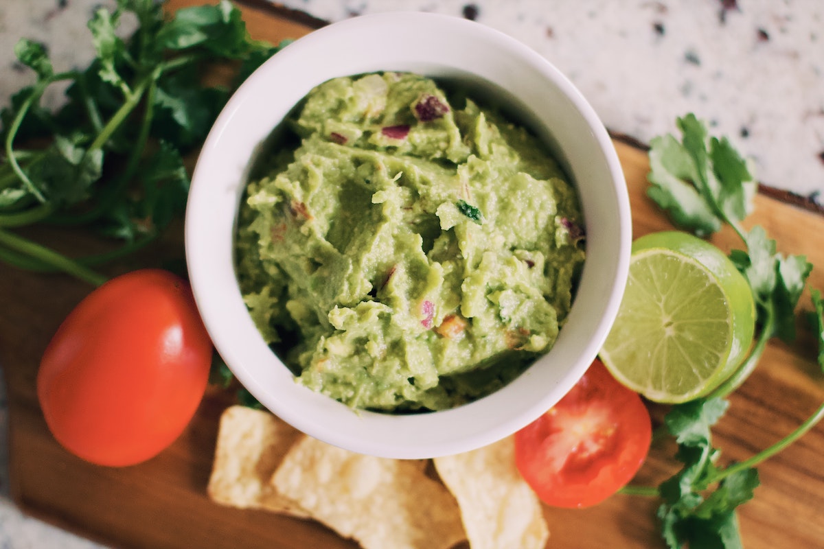avocado in guacamole form with lime and tomatoes