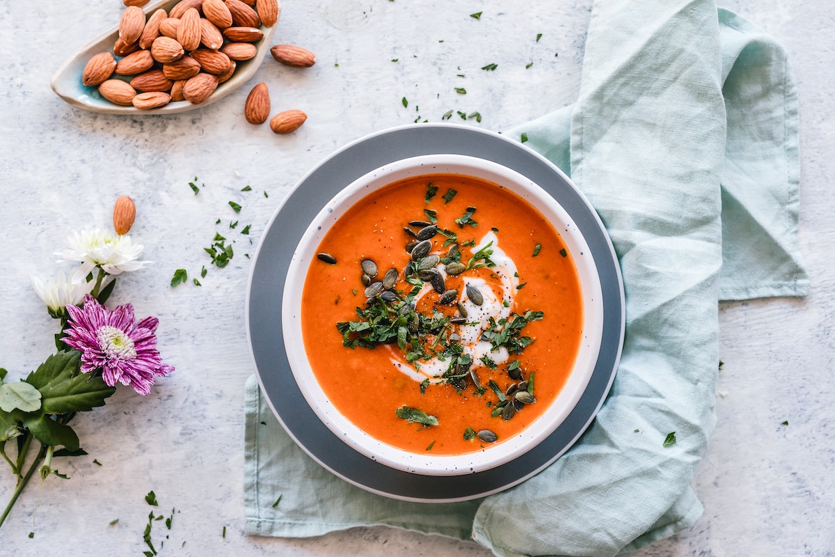 tomato soup with cream and herbs surrounded by flowers and almonds