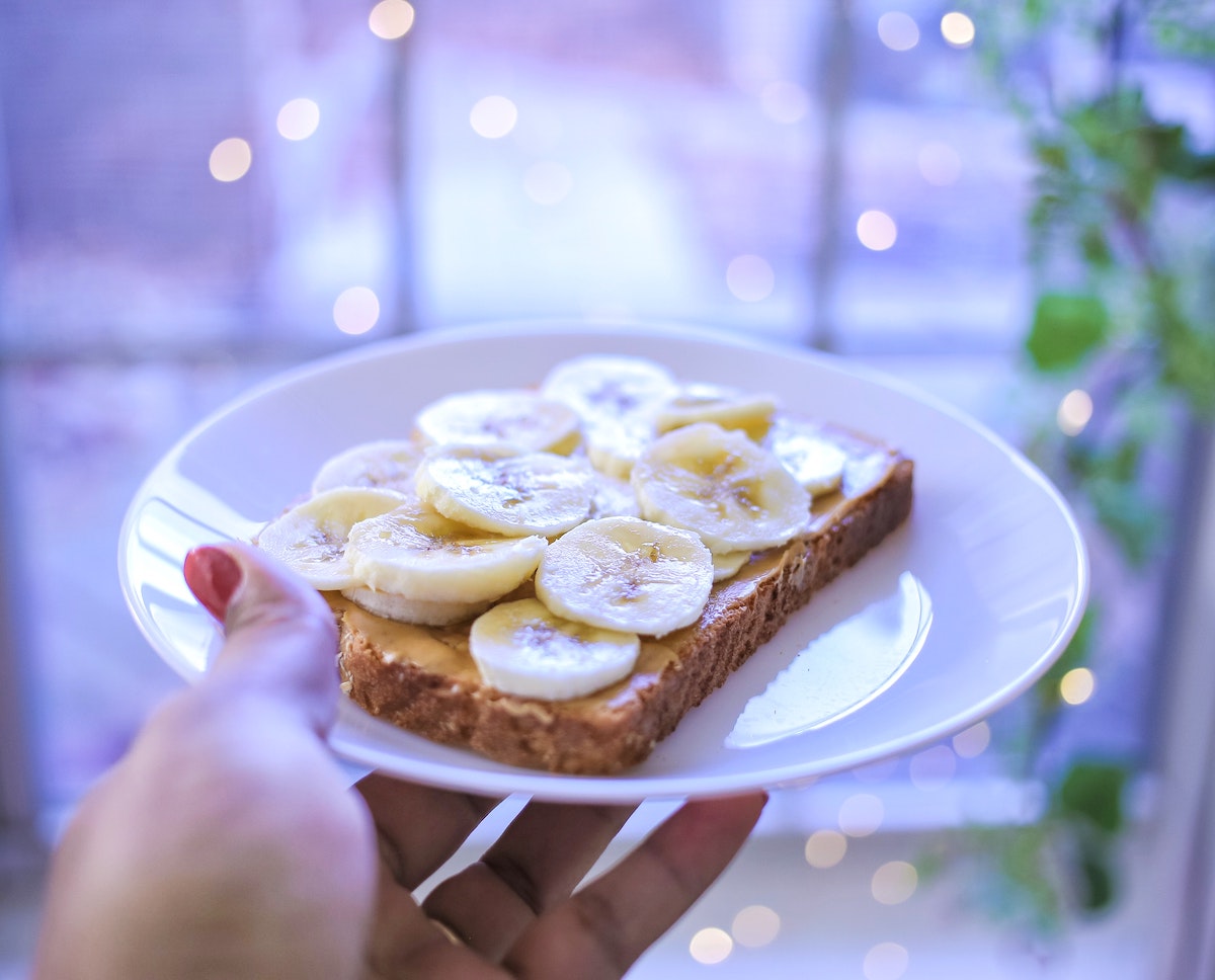 person holding plate of banana and peanut butter bread
