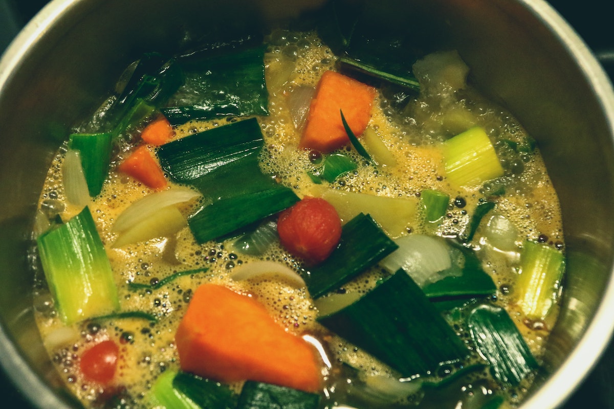 vegetable soup broth in bowl carrots greens onions tomato