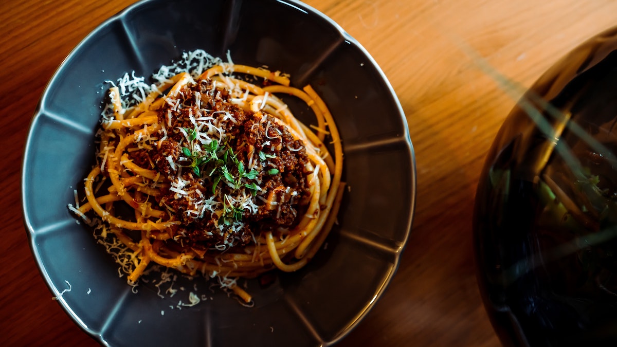 spaghetti bolognese topped with parmesan and herbs