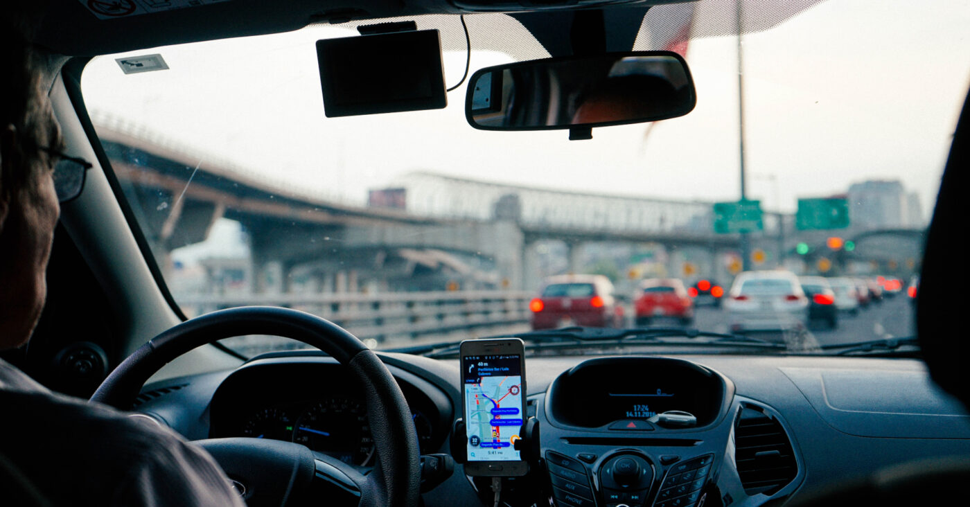 man with glasses driving with GPS on phone. cheap first cars to insure article