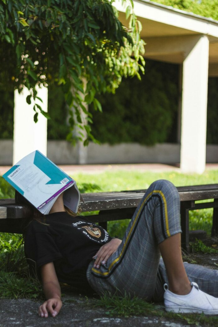 person with head under book looking tired - academic burnout