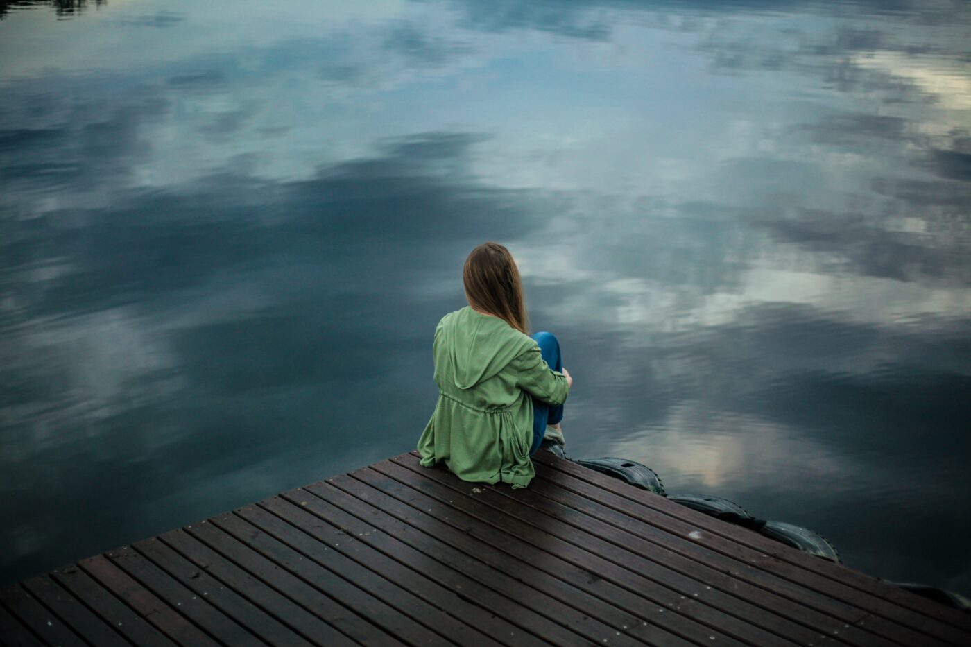 Anxious girl sat by a lake 