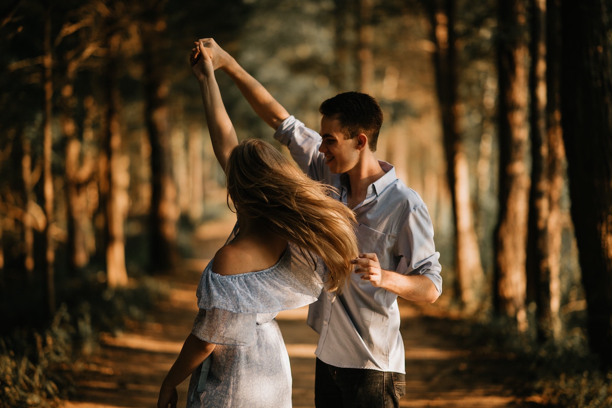 couple spinning lady around in woods