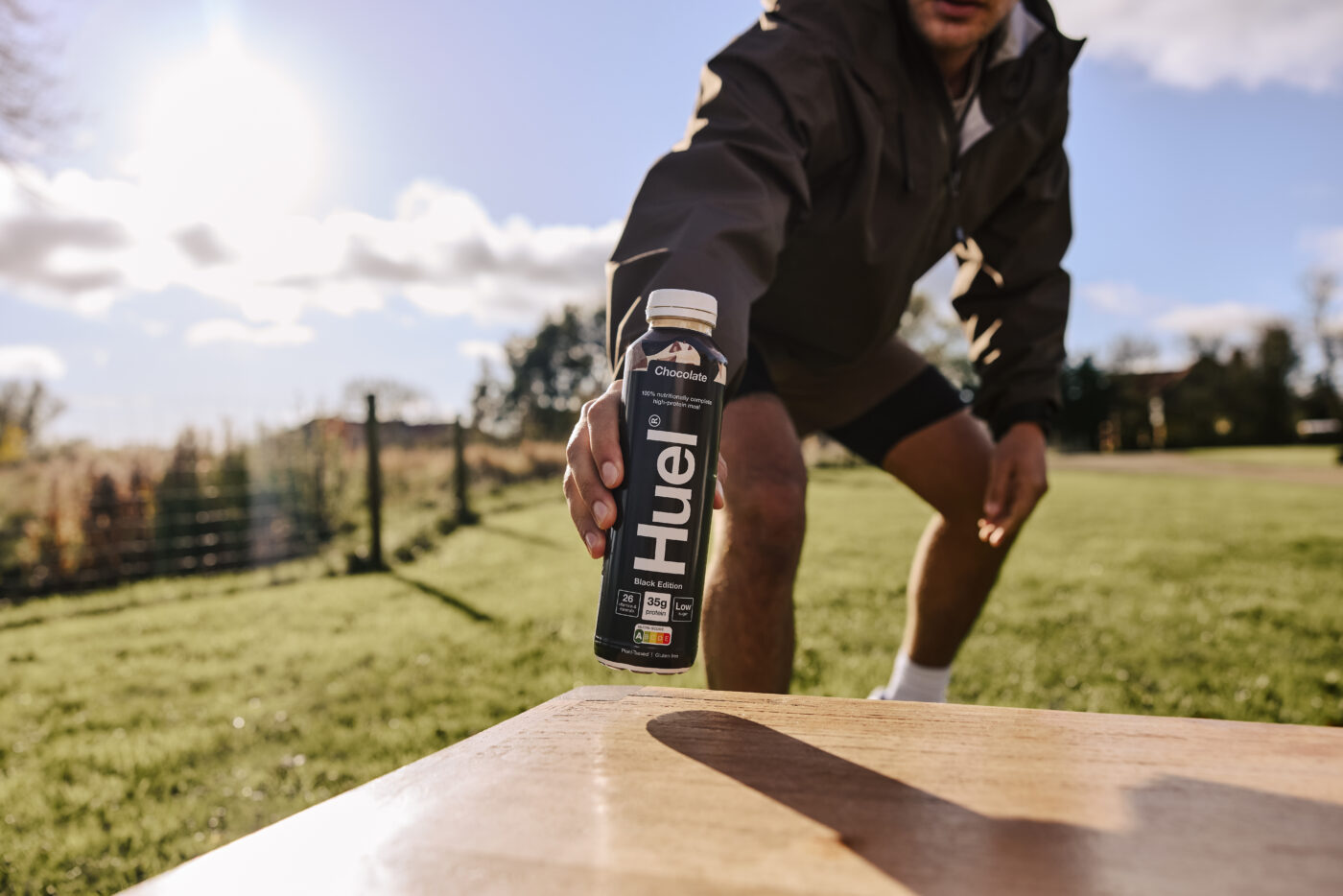 Man leaning down to pick up a bottle of Huel drink