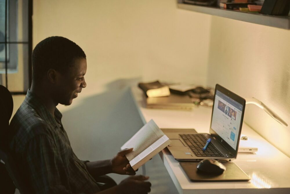 Man sat at laptop holding his book